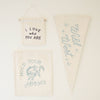 The "I Love Who You Are" Natural Canvas Sign is a cream-colored, handmade wall hanging—perfect as unique Kenyan artisan decor or an inspirational accent to any space.