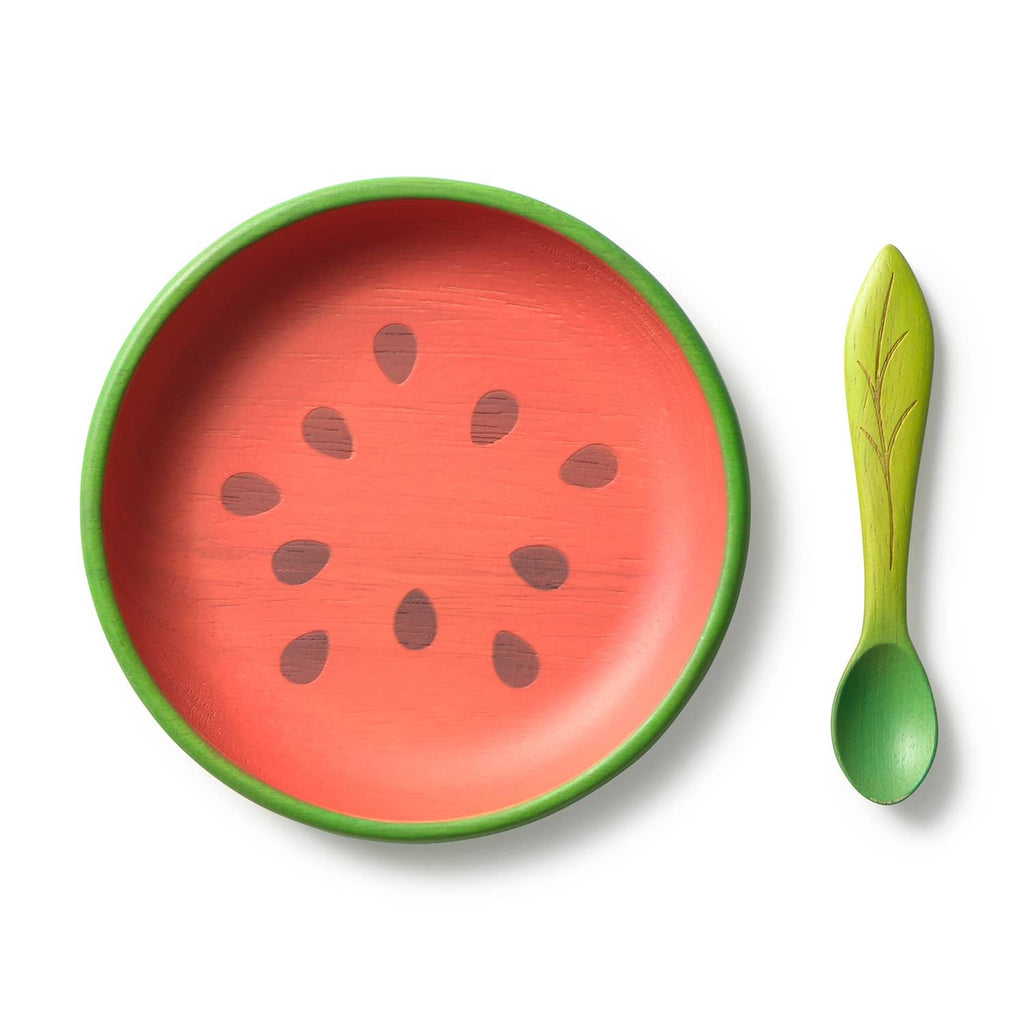 The Wally the Watermelon Plate & Spoon Set features a round Hevea wood plate styled like a watermelon slice with green edges and black seeds, paired with a green leaf-handle spoon—charming, non-toxic tableware for baby meals.