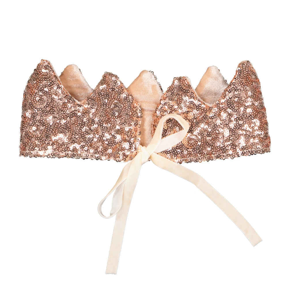 Introducing the Crown - Pink Sequins: a sparkly, rose gold pointed crown adorned with a white ribbon at the front. This crown is embellished with sequins that create a shimmering appearance, perfect for aspiring Queens or apprentice fairies.