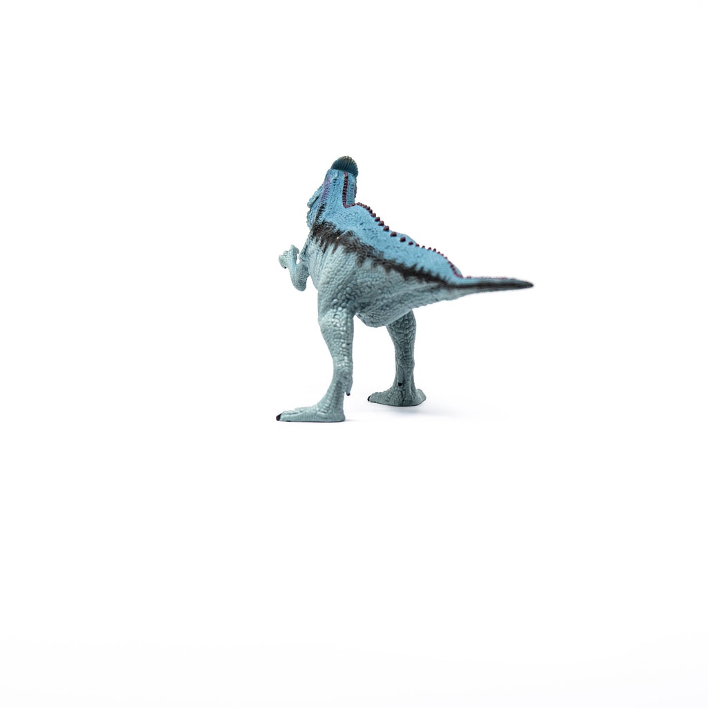 A Schleich Cryolophosaurus Dinosaur Toy with Movable Jaw, featuring a small blue body with black stripes, stands on a white background facing away from the camera.