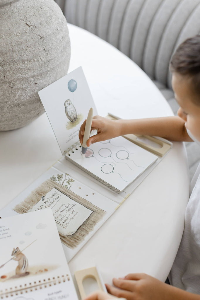 A child uses a water pen to color in balloon illustrations on a page of the Winnie-the-Pooh: Pooh’s Birthday Surprise (Water Reveal) book.