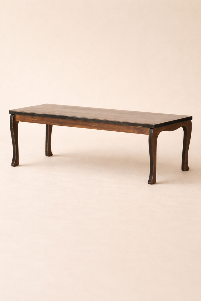 The Maileg Dining Room Set features a low rectangular table with a dark finish and elegant curved legs, displayed against a plain light beige background.