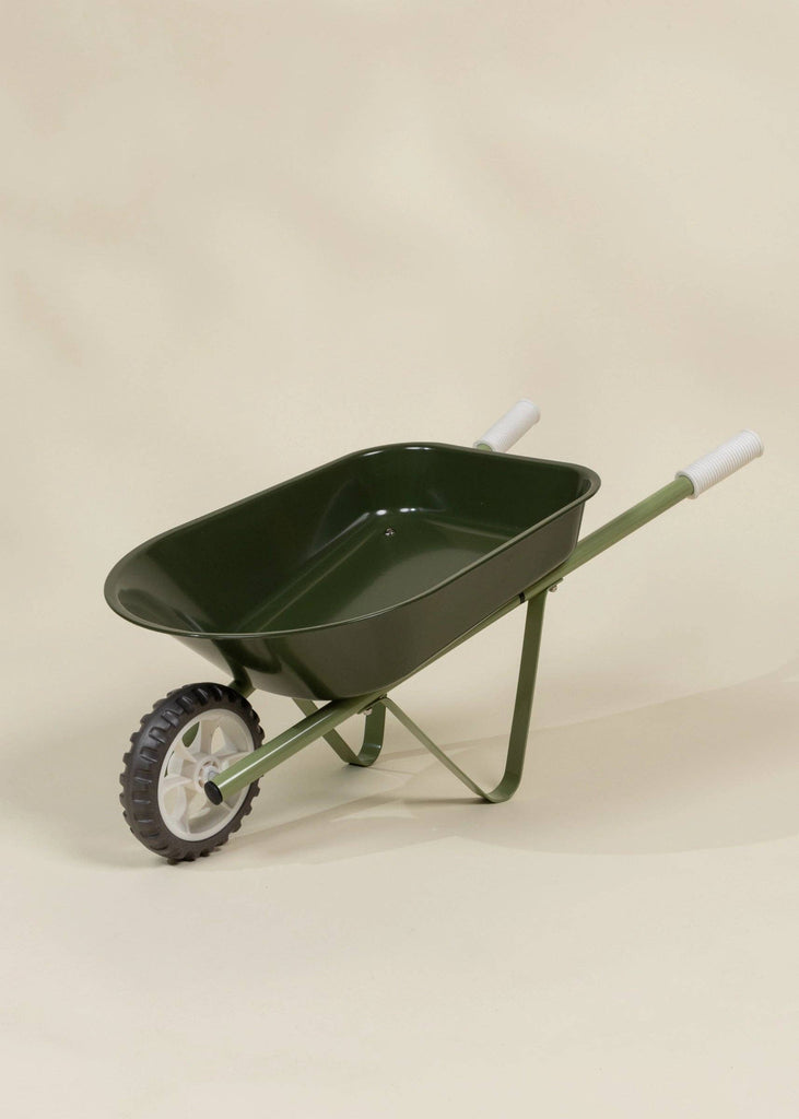 The Heritage Wheelbarrow – Liane, a green children’s wheelbarrow with white handles and a black-and-white wheel, is set against a light beige background—ideal for kids’ outdoor gardening activities.