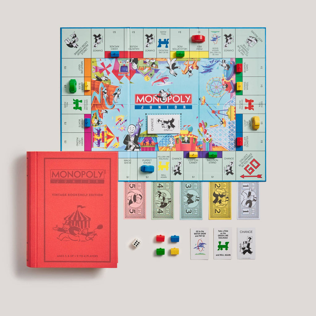 Monopoly Junior Vintage Bookshelf Edition game set including a square game board, a red book-shaped storage box, four character tokens, a die, and a deck of cards.