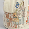 The Coral & Tusk Easter Parade Basket showcases embroidered woodland creatures like a cat and bird, dressed in outfits and holding flowers. Detailed stitching enhances its felt interior, offering a charming handmade look against a plain light gray surface.