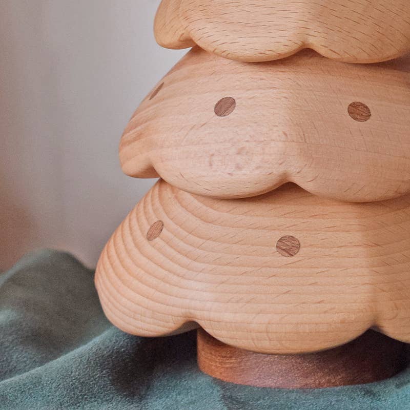 A close-up of the Christmas Tree Storage Box, designed with scalloped layers and circular dots, placed on a green fabric surface.