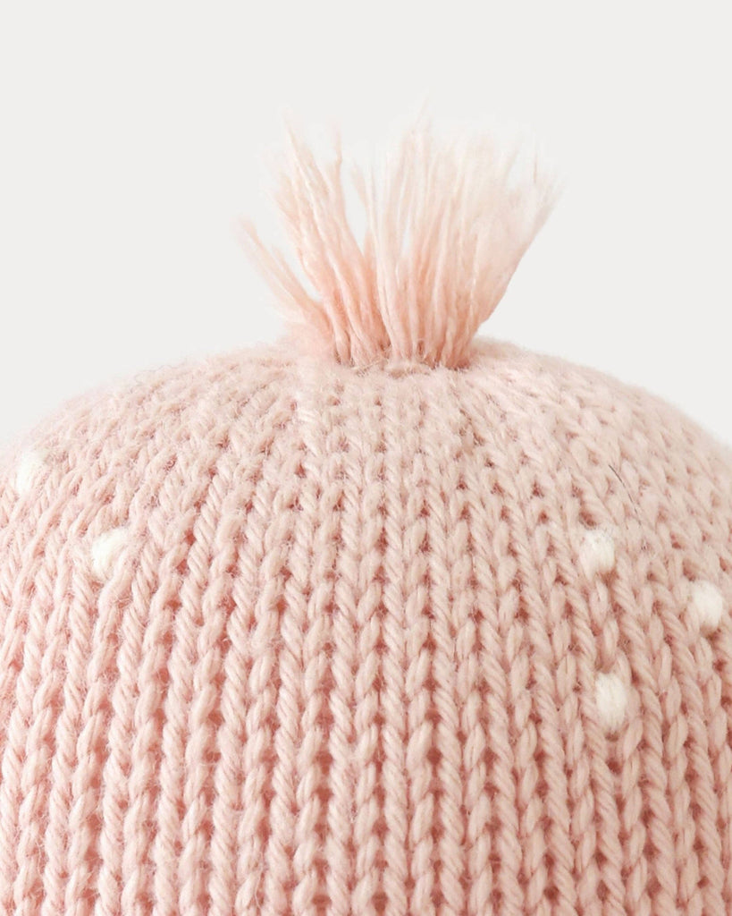 Close-up of the Cuddle + Kind Baby Octopus in Soft Coral Pink, featuring heirloom-quality Peruvian cotton yarn and a plush pom-pom top, shown against a plain light background.