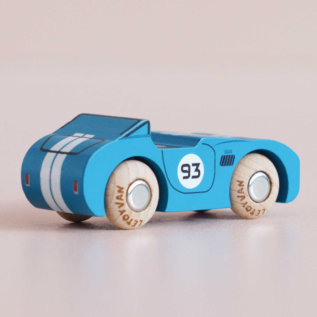 The No. 5 GT30 Coby, made in England, is a small blue wooden race car featuring white racing stripes, the number 93 on the side, and light-colored wheels—a classic racing toy that makes a charming addition to any collection.