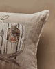 A close-up of the Coral & Tusk Aspen Log Bunnies Pocket Pillow shows a beige linen pillow embroidered with tree trunks and a removable rabbit in an orange patterned shirt peeking from a tree hollow.