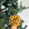 A Fluffy Lion Finger Puppet, perfect as a storytelling prop and handmade in Nepal, is held up in front of a green, blurred-out background. Made of yellow and brown felt, the lion has a fluffy mane, black eyes, and a small black nose with a neutral expression on its face.