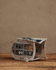 A Coral & Tusk Haunted House Tissue Box Cover, embroidered with charming animal illustrations, rests tipped over on a wooden surface against a plain beige background.