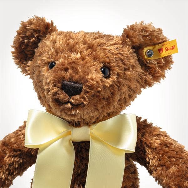 The Steiff Cosy Year Bear 2026 13" is a brown plush teddy with curly fur, shiny black eyes, black nose, pale yellow satin bow, and yellow Steiff ear tag—an ideal New Year 2026 gift—shown against a white background.