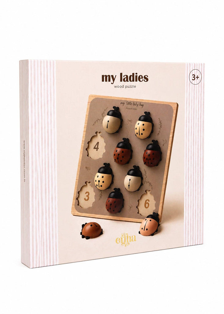 Introducing the My Little Lady Bug Wooden Puzzle—a boxed wooden peg puzzle designed for children ages 3 and up. This Montessori-inspired counting toy features ladybug-shaped pieces with numbered spots, perfect for early learning. The packaging showcases a white background accented with light pink stripes along the sides.