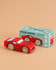 A red wooden sports car, crafted from sustainable wood, is displayed next to its box—which reads “No. 18 GT100 Jasper | Made in England” and features an illustration of the car on a green background. This classic collectible combines timeless style with eco-friendly materials for the ultimate performance motoring display piece.