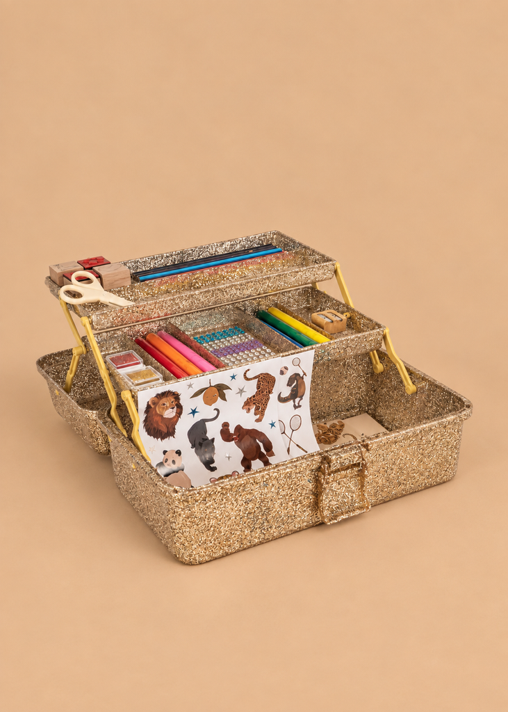 The Konges Sloejd Creative Art Caddy - Tiger, an open glittery gold toolbox filled with kids’ art supplies—colored markers, crayons, scissors, a ruler, glue, and a sheet of animal stickers—invites imaginative play on a beige background.