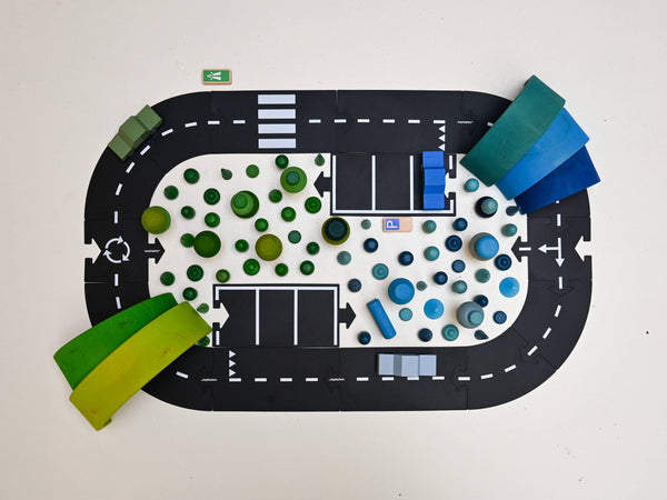 The WaytoPlay: Medium Flexible Toy Road Set - Expressway includes 16 black road pieces, colorful wooden blocks as buildings and trees, plus small signs—perfect for sparking imaginative city or park racetrack layouts on any surface.