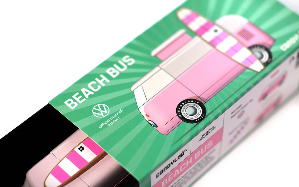 A close-up of the VW Beach Bus Pink box, showing a pink and white Volkswagen Type 2 van with a surfboard on the roof, VW logo, and green packaging.