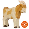 A Holztiger Billy-Goat, handcrafted out of wood with a natural finish and patches of brown paint, stands on four legs. The toy features simple carved details for the eyes and horns. An orange sticker on the bottom right reads "spiel gut," indicating it's a highly recommended children's toy made in Europe.