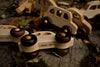 Several Little Wooden French Cars, each handcrafted from natural wood with dark wheels and a smooth finish, rest outdoors on a rustic surface among dry leaves. Each eco-friendly baby toy is branded "WOODEN STORY.