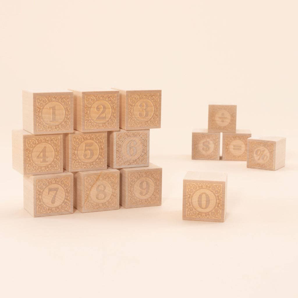 Uncle Goose Number Alphablank Blocks feature basswood blocks with numbers 0-9 stacked on the left and four blank wood cubes showing math symbols (+, –, =, %) on the right, all set against a plain light background.