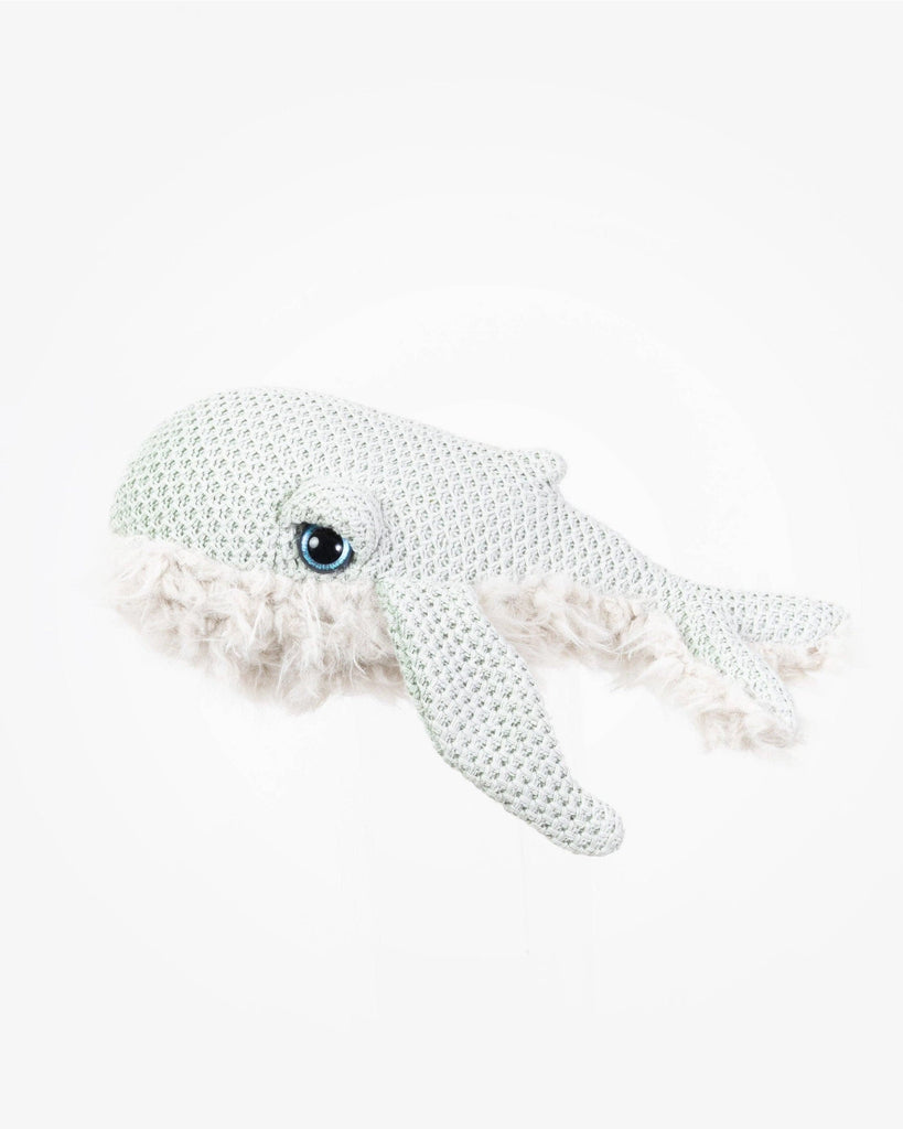 A BigStuffed Mini Grandma Whale, this crocheted white whale plush toy with a textured surface and a large, blue eye is expertly handcrafted. Detailed fins and a tail, along with fuzzy white yarn around its mouth, give it a whimsical appearance. Made in Lithuania, the background is plain white.