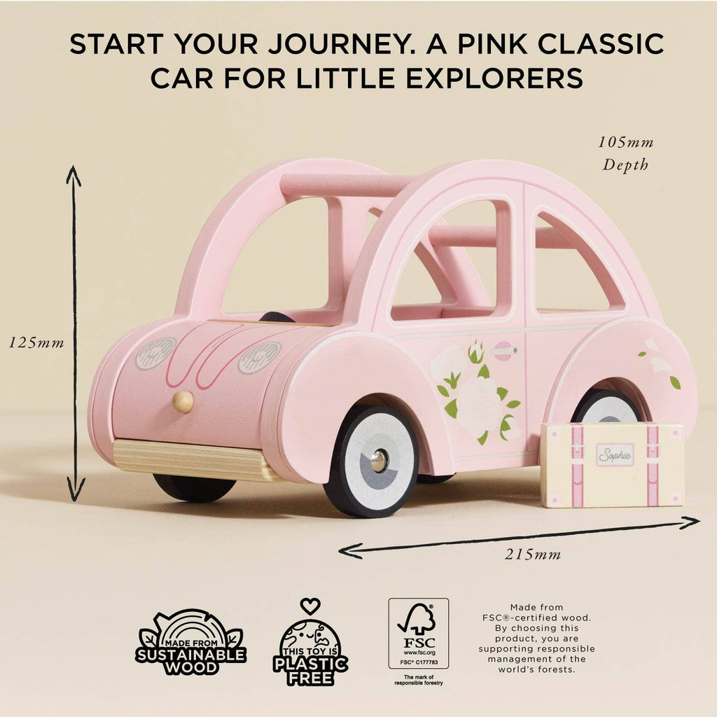 Sophie's Dolls House Toy Car, a pink retro wooden car with floral details, is shown beside a small suitcase. Dimensions: 125mm H x 215mm W x 105mm D. This educational toy is eco-friendly and plastic-free.
