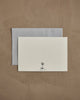 The Coral & Tusk Snowman Card features a blank white card with a tree and anchor logo above "CORAL & TUSK," set on a light gray envelope atop a brown textured surface—perfect for season’s greetings or winter decor.