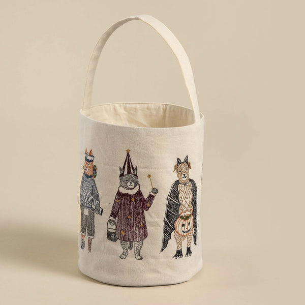 A cream-colored Trick or Treat Small Bucket embroidered with whimsical characters: a knight, a witch, and a gentleman fox, each in detailed costumes. The bag has a sturdy handle and a flat bottom. Ideal
