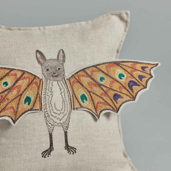 Bat Wing Surprise Pillow featuring an embroidered design of a fantastical creature with bat's wings and a squirrel-like body, against a solid light gray background, enhanced with magnetic fabric wings.