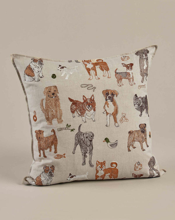 Coral & Tusk Dogs and Toys Pillow featuring a variety of embroidered dog illustrations in different poses and breeds on a neutral beige background.