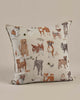 Coral & Tusk Dogs and Toys Pillow featuring a variety of embroidered dog illustrations in different poses and breeds on a neutral beige background.