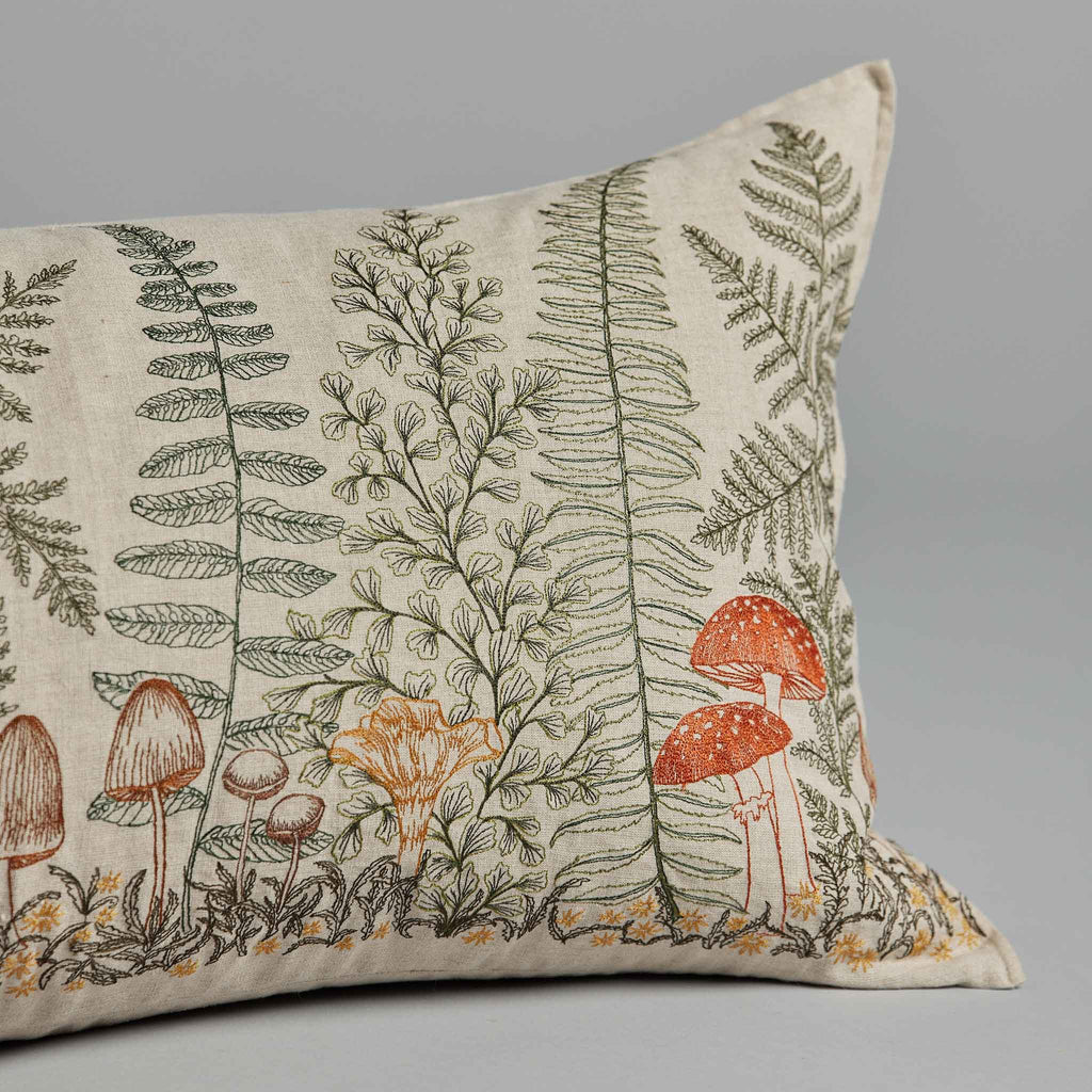 Coral & Tusk Mushrooms and Ferns Lumbar Pillow with an embroidered botanical print featuring detailed illustrations of ferns and various mushrooms on a neutral background.