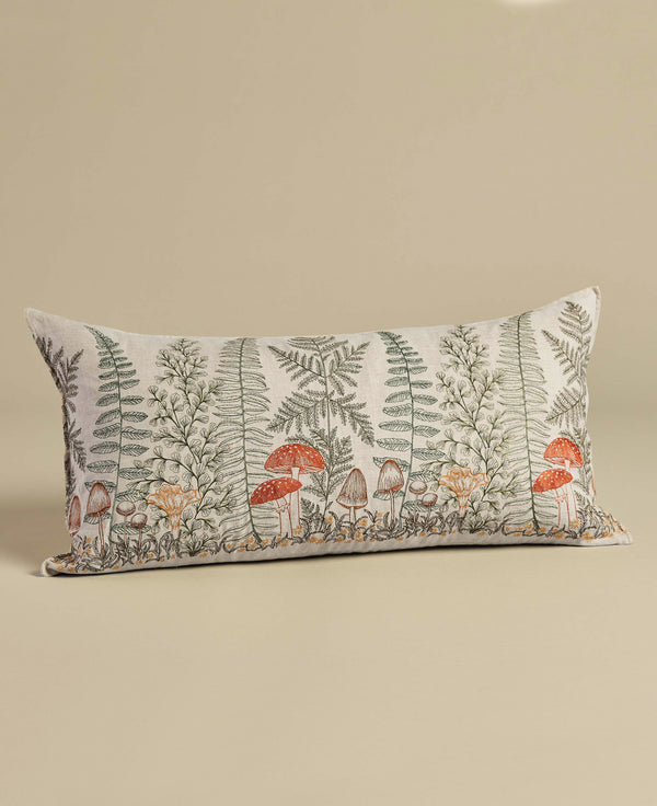 Rectangular decorative Coral & Tusk Mushrooms and Ferns Lumbar Pillow featuring a botanical and mushroom print on a cream background, displayed against an embroidered shade garden surface.