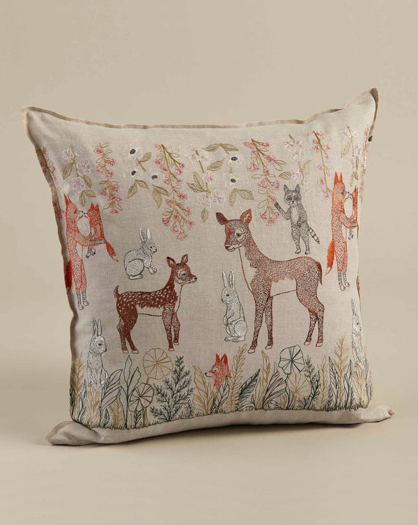 Coral & Tusk Spring Blossoms Pillow featuring linen fabric with a whimsical forest scene, showcasing embroidered foxes, deer, rabbits, and foliage in soft, earthy tones.