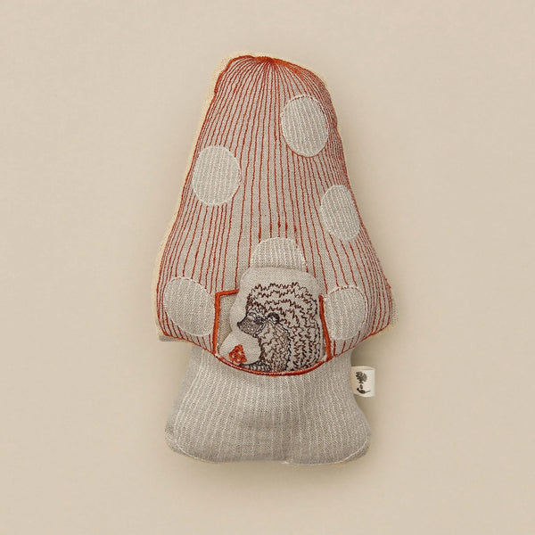 A handmade plush Coral & Tusk Pocket Mushroom toy with red stitching, white polka dots, and a small embroidered hedgehog peeking through a circular window near its base, presented against a neutral background.