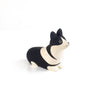 A small, hand-carved figurine of a dog with black and white coloring, resembling a corgi. Crafted by Albizia wood artisans, the Handmade Tiny Wooden Animals - Corgi Dog is sitting with a minimalist design, smooth edges, and distinct black eyes. This charming handmade wooden animal is set against a plain white background.