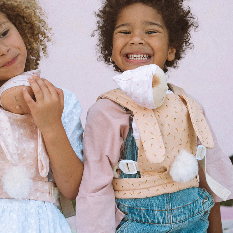 Two joyful children laughing, one holding an ice cream cone. They wear whimsical outfits with one in a denim bib and the other in a pink, Olli Ella x Odin Parker Dinkum Dolls Cottontail Carrier – Hopscotch star-de