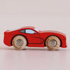A No. 18 GT100 Jasper, a red wooden sports car with black details and wooden wheels, crafted from sustainable wood in England, sits on a light surface, viewed from the side.
