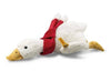 A cozy companion, the Steiff Gilda Christmas Goose plush lies on its stomach, featuring a white body, yellow beak and feet, and a festive red scarf.