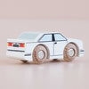 The No. 21 GT120 William | Made in England is a white wooden toy car featuring black accents and wooden wheels, displayed on a light surface and photographed from the rear left side.