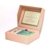 A pink box with a propped lid reveals the Memory Game - Festival of Flowers, a memory game featuring charming watercolor flower illustrations. The game's instructions are printed on the inner lid.
