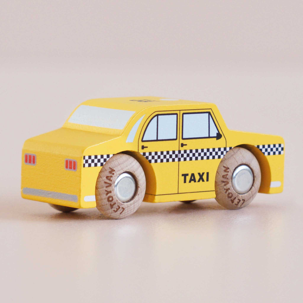No. 39 GT245 Trixie, a small yellow wooden taxi handmade in England and inspired by the classic New York taxi, features black and white checkered detailing and cork wheels—perfect for imaginative play on any surface.