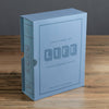 A light blue book-shaped box labeled "Board Game: The Game of Life Vintage Bookshelf Edition" rests on a wooden surface. This classic game is ideal for ages 9+, perfect for 2 to 6 players.