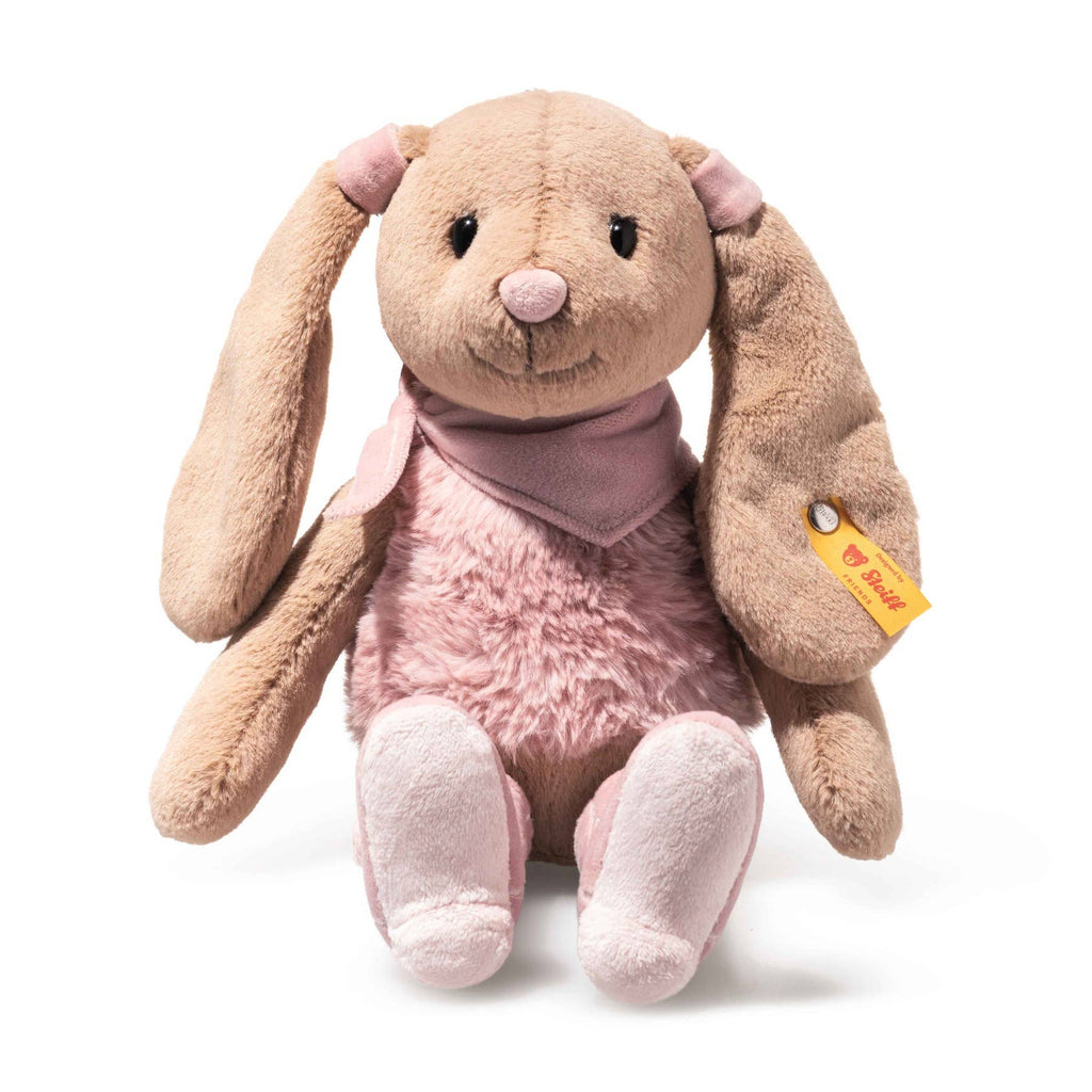 The Steiff Cowgirl Hoppie Rabbit is a plush bunny with long floppy ears, light brown fur, a pink nose, pink belly and feet, a pink scarf around its neck, and a yellow tag on its left ear for extra charm.