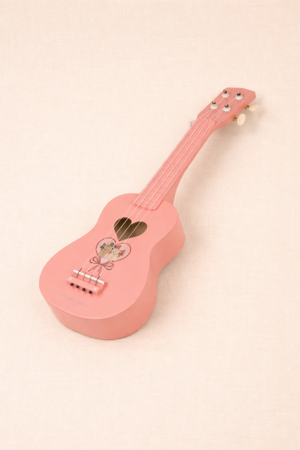 The Wooden Ukulele - Bow Kitty is a small pink 4-string instrument with a heart-shaped sound hole and floral design, displayed on a light beige background.