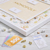 Monopoly Bianco Edition board game set featuring a white and gold foil-stamped board, dice, metal tokens, houses, hotels, paper money, and property cards.