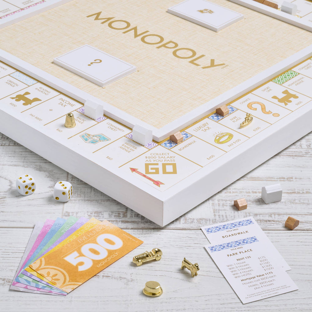 Monopoly Bianco Edition board game set featuring a white and gold foil-stamped board, dice, metal tokens, houses, hotels, paper money, and property cards.