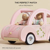 A pink retro Sophie's Dolls House Toy Car with floral details carries two smiling wooden dolls in pastel outfits. Text above: "The Perfect Match with our Dolly Family Set." Note: Dolls sold separately.