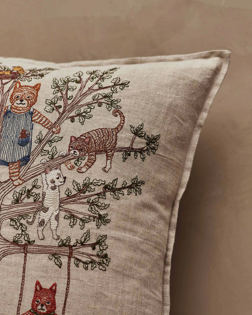 A close-up of the Coral & Tusk Tree of Fun Pillow, featuring beige fabric with embroidered cats climbing and playing on tree branches. The detailed stitching captures the playful spirit and charm of this whimsical pillow.