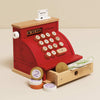 The Cash Register & Money is a red wooden toy by Le Toy Van featuring buttons, a receipt, play money, coins, and an open cash drawer with bills. Its charming design makes it an educational, child-friendly pretend play toy.